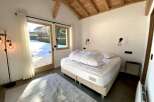 This stunning bedroom boasts a cozy and modern design, featuring a comfortable bed with crisp white linens and a plush duvet.
