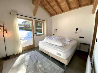 This stunning bedroom boasts a cozy and modern design, featuring a comfortable bed with crisp white linens and a plush duvet.