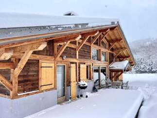 This stunning chalet boasts a beautiful wooden exterior, large windows offering breathtaking views, and a spacious deck perfect for outdoor entertaining.