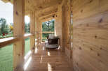 Relax on the spacious wooden deck overlooking a lush green landscape.