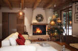 Cozy up by the fireplace in this stunning mountain chalet, complete with a beautifully decorated Christmas tree and comfortable seating.