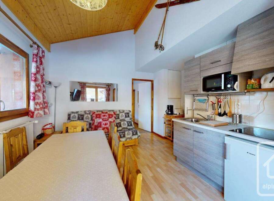 Cozy studio apartment in the French Alps with a fully equipped kitchenette, including a microwave, stovetop, and refrigerator.
