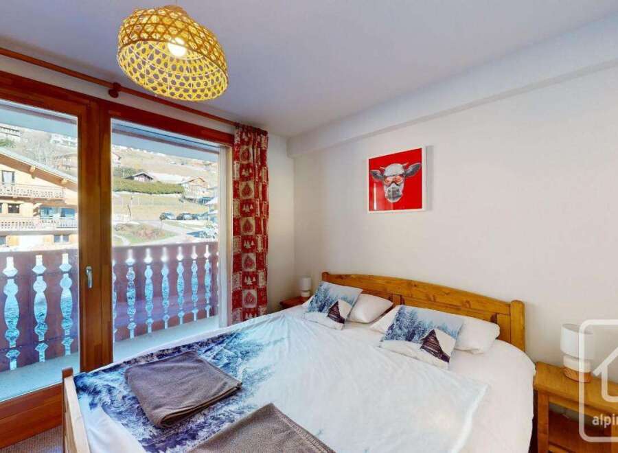 Cozy bedroom with a double bed, featuring winter-themed bedding and a balcony offering stunning mountain views.