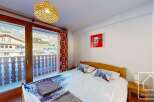Cozy bedroom with a double bed, featuring winter-themed bedding and a balcony offering stunning mountain views.