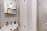 This modern bathroom boasts a sleek, corner sink with a mirrored medicine cabinet above, offering ample storage and counter space.