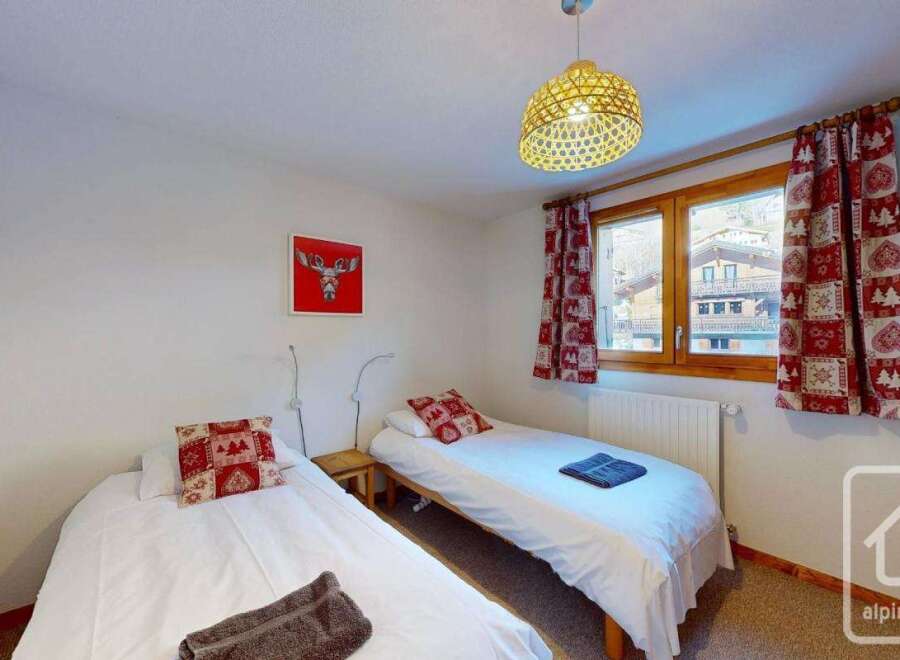 Cozy twin bedroom with mountain views, featuring two single beds, festive decor, and a warm atmosphere.