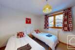 Cozy twin bedroom with mountain views, featuring two single beds, festive decor, and a warm atmosphere.