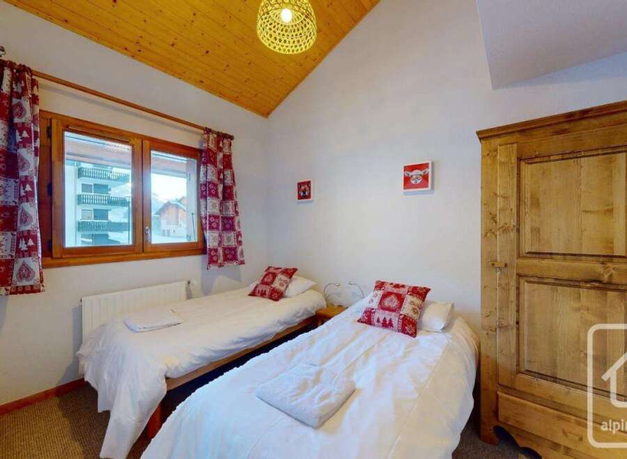 Cozy twin bedroom with wooden wardrobe and mountain views.