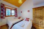 Cozy twin bedroom with wooden wardrobe and mountain views.