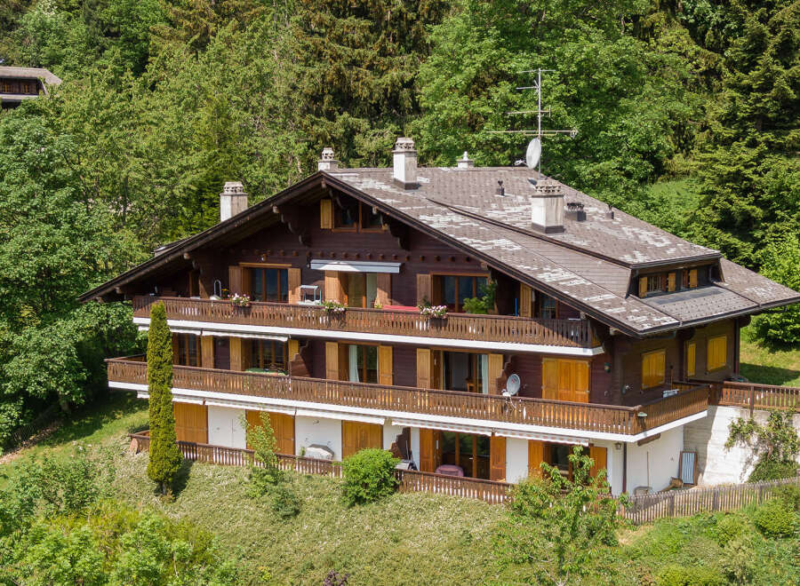 Nestled amidst lush greenery, this stunning property boasts a classic chalet design with multiple levels of balconies.