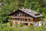 Nestled amidst lush greenery, this stunning property boasts a classic chalet design with multiple levels of balconies.