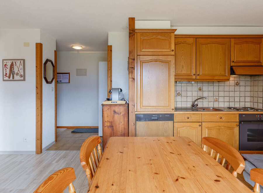 Discover a cozy kitchen with wooden cabinets and a dining table, perfect for enjoying meals.