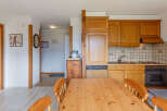 Discover a cozy kitchen with wooden cabinets and a dining table, perfect for enjoying meals.