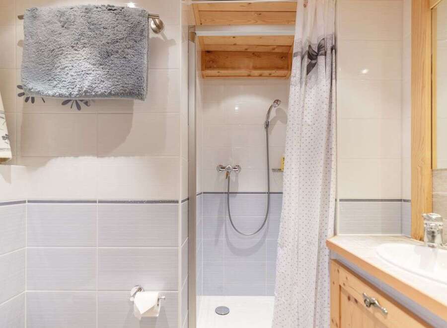 This charming bathroom features a cozy shower area with a stylish curtain.
