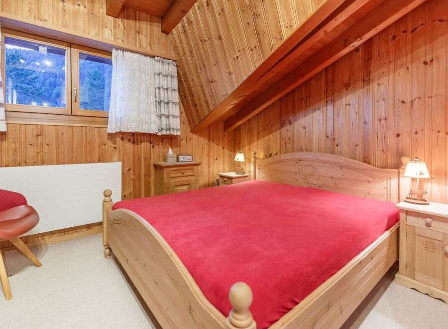 Cozy bedroom with wooden walls and a comfortable bed.