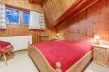 Cozy bedroom with wooden walls and a comfortable bed.