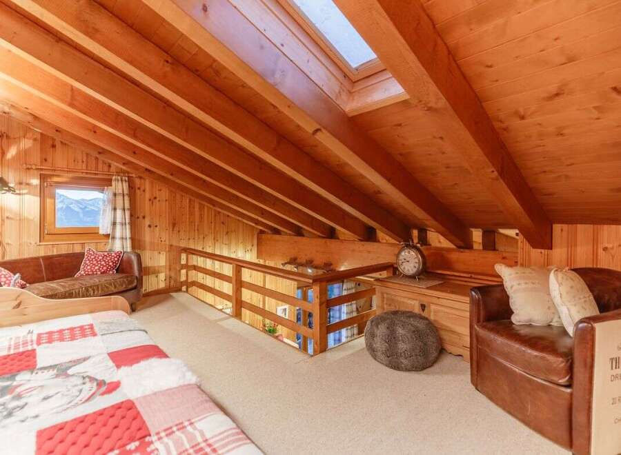 This cozy attic space features a warm wooden interior and a skylight that floods the room with natural light.