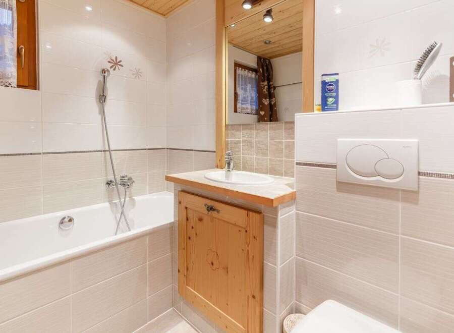 This charming bathroom features a cozy wooden ceiling and a stylish wooden vanity.