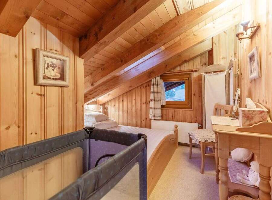 Cozy attic bedroom with wooden paneling and exposed beams.