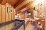 Cozy attic bedroom with wooden paneling and exposed beams.