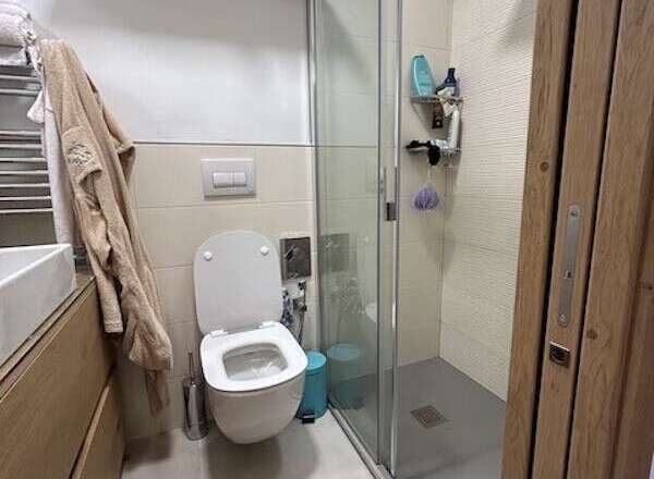 This modern bathroom features a sleek, minimalist design with a walk-in shower and a contemporary toilet.