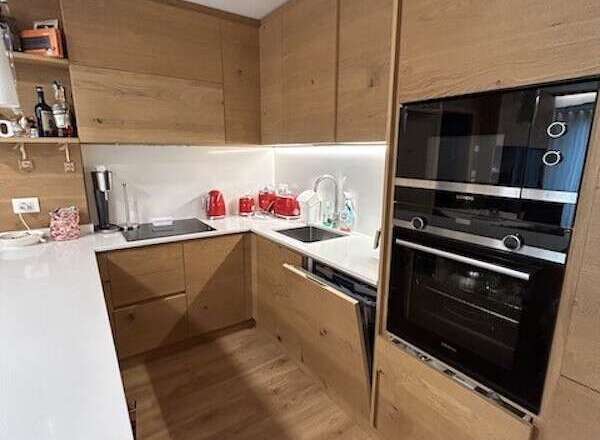This modern kitchen boasts sleek wooden cabinetry and flooring, creating a warm and inviting atmosphere.