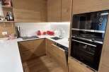 This modern kitchen boasts sleek wooden cabinetry and flooring, creating a warm and inviting atmosphere.
