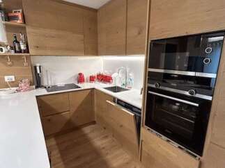 This modern kitchen boasts sleek wooden cabinetry and flooring, creating a warm and inviting atmosphere.