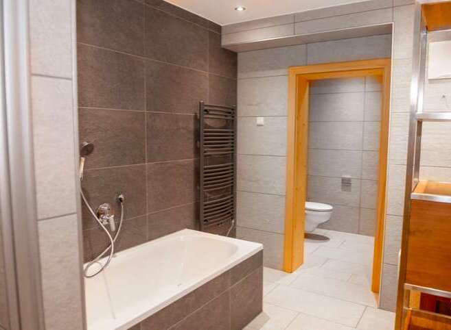 This modern bathroom features a sleek design with tiled walls and a comfortable bathtub.