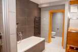 This modern bathroom features a sleek design with tiled walls and a comfortable bathtub.