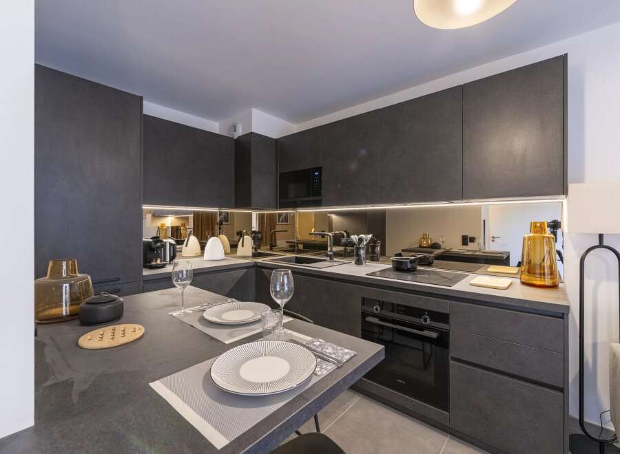 This modern kitchen boasts sleek, dark gray cabinetry and countertops, creating a sophisticated and contemporary ambiance.