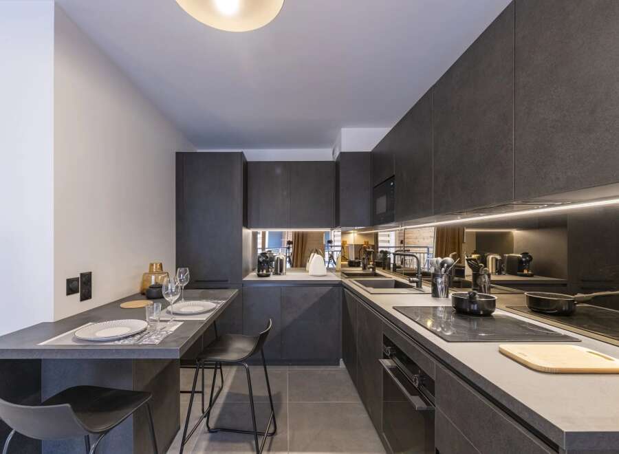 This modern kitchen boasts sleek, dark cabinetry and countertops, creating a sophisticated and stylish space.