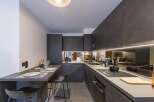 This modern kitchen boasts sleek, dark cabinetry and countertops, creating a sophisticated and stylish space.