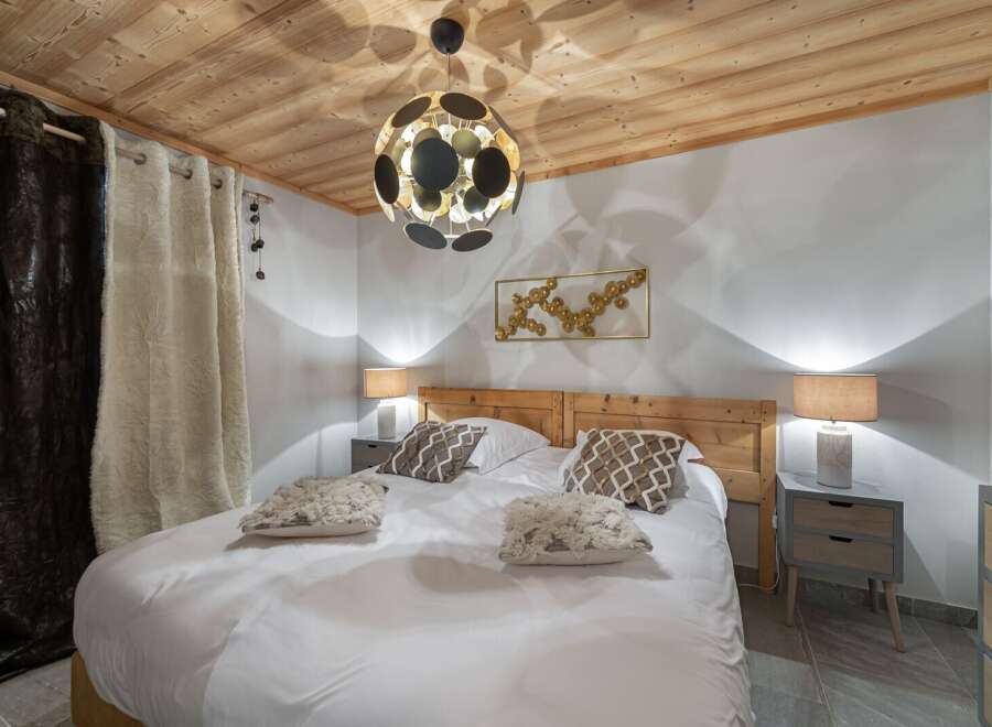 Discover a cozy bedroom retreat with a rustic wooden ceiling and a comfortable bed.