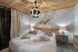 Discover a cozy bedroom retreat with a rustic wooden ceiling and a comfortable bed.