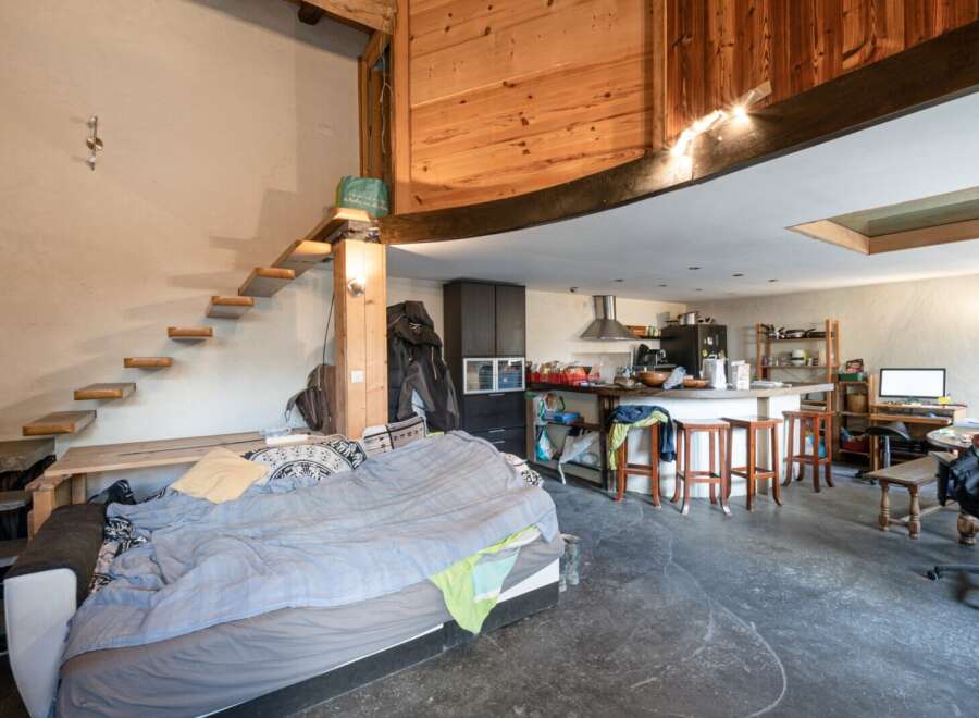 Discover a unique living space with a loft-style design, featuring a cozy bed area and a modern kitchen.