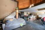 Discover a unique living space with a loft-style design, featuring a cozy bed area and a modern kitchen.