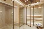 Indulge in luxury within this spa-like bathroom, featuring multiple glass-enclosed showers with elegant gold framing.