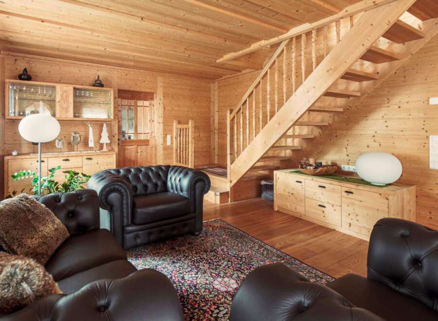This stunning log cabin boasts a spacious living area with plush leather furniture and a beautiful oriental rug.