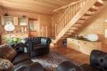 This stunning log cabin boasts a spacious living area with plush leather furniture and a beautiful oriental rug.