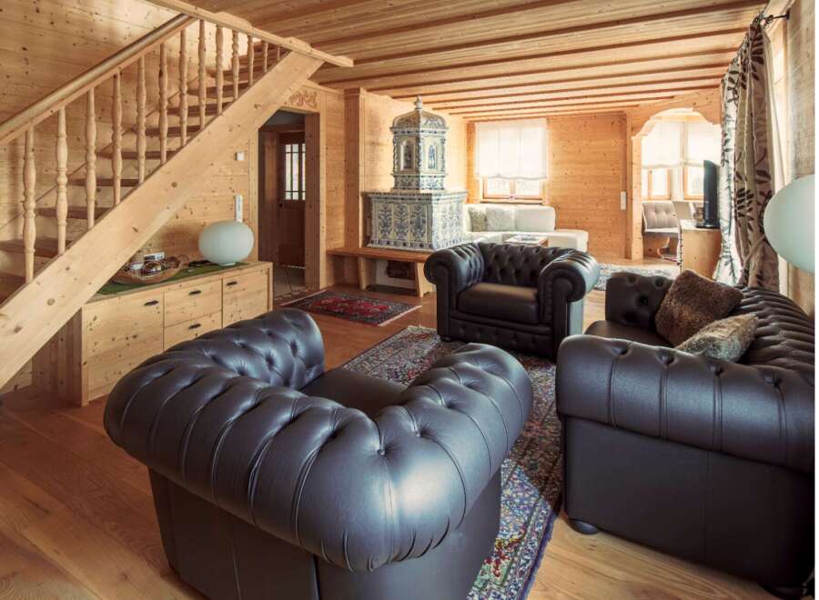 This stunning chalet boasts a spacious living area with comfortable leather armchairs and a beautiful tiled stove.