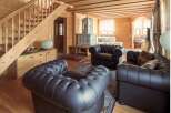 This stunning chalet boasts a spacious living area with comfortable leather armchairs and a beautiful tiled stove.