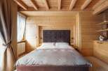 Cozy up in this stunning bedroom, featuring a plush bed and wooden walls and ceilings.