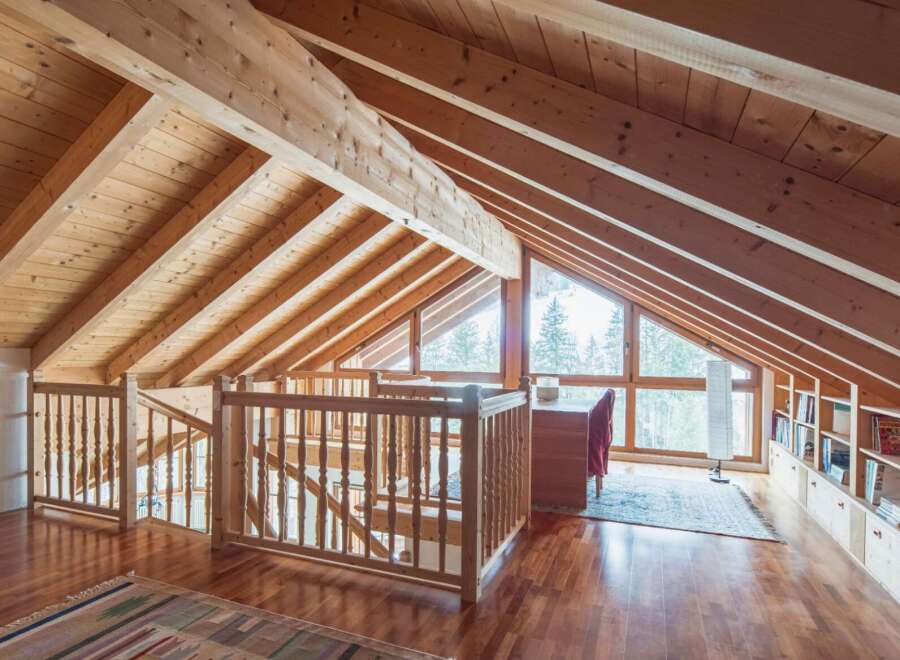 This stunning attic boasts a beautiful wooden interior with exposed beams and a large window offering breathtaking views.