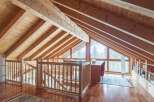This stunning attic boasts a beautiful wooden interior with exposed beams and a large window offering breathtaking views.
