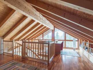 This stunning attic boasts a beautiful wooden interior with exposed beams and a large window offering breathtaking views.