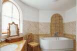 Luxury bathroom with a freestanding bathtub and arched window.