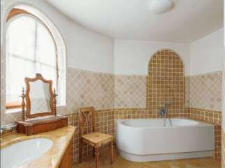 Luxury bathroom with a freestanding bathtub and arched window.