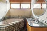 Luxurious bathroom with a corner jacuzzi tub and a large, round mirror.