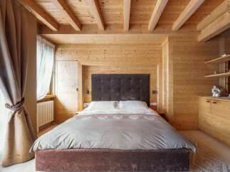 Cozy up in this stunning bedroom, featuring a plush bed and wooden walls and ceilings.